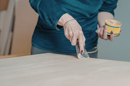 Woman applying wood finish to a table