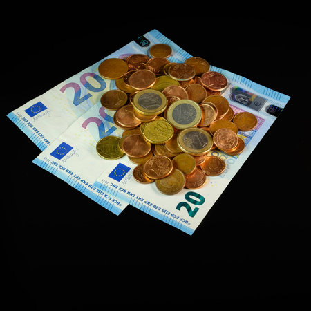 Euro coins and banknotes on a black background
