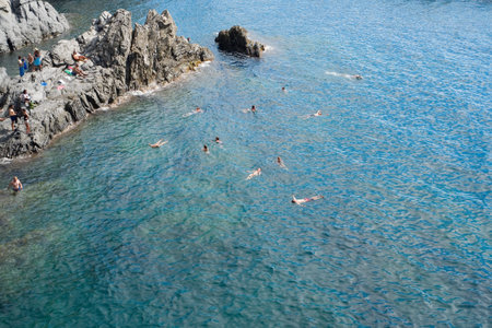 Manarola, Italy- September 17, 2018: Bathers relax and swim in the beautiful sea of Liguria in the...