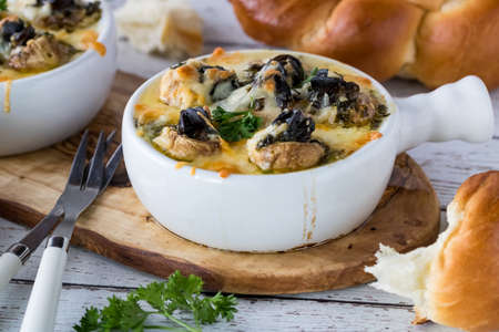 Close up view of a dish with escargot stuffed mushroom caps topped with melted cheese and hot garlic butter ready for eating.の写真素材