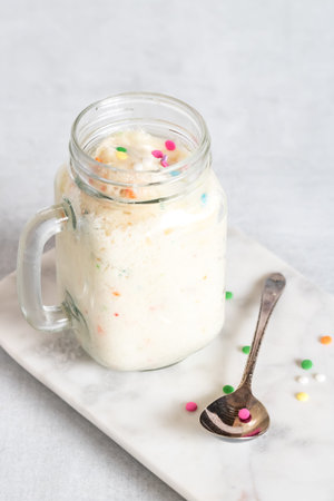 A top down view of a jar of confetti cake with a spoon of confetti in front.