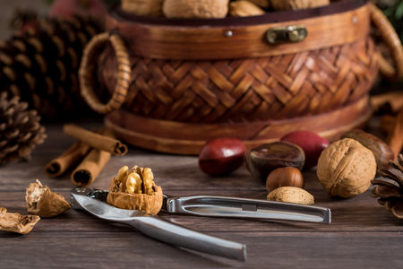 A close up view of a basket filled with mixed nuts with a walnut cracked open in front.