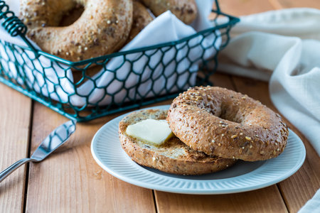 A close up view of a multi grain bagel with butter ready for eating.