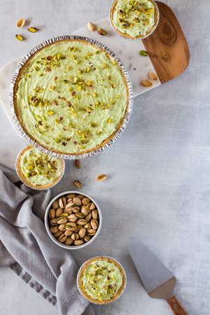 A flat lay view of a variety of pistachio cheesecakes and a bowl of pistachios, with copy space to...