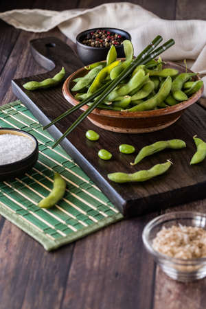 Close up of a rustic bowl filled with fresh organic edamame beans in their pods.の写真素材