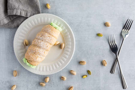 Top down view of a pistachio cannolo surrounded by pistachios ready for eating.の写真素材
