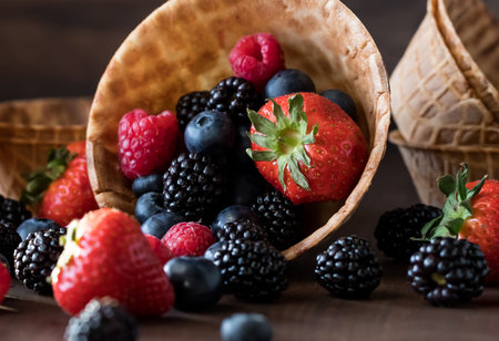 A macro close up view of a variety of berries spilling out of a waffle bowl. Delicious dessert...