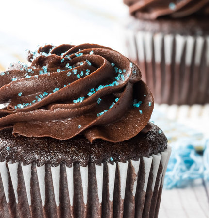 Macro close up view of a chocolate cupcake with chocolate frosting and blue sprinkles ready for eating.の写真素材