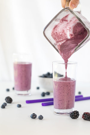 Freshly blended berry smoothie being poured into a glass.
