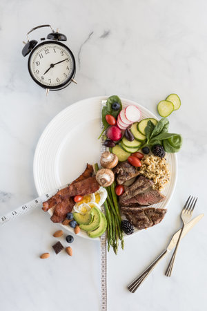 16:8 Intermittent fasting weigh loss concept. Various low carb foods on a white plate with a portion...