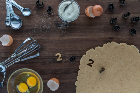 Top down view of a baking scene with baking utensils, ingredients and number cookie cutters using...