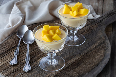 Mango mousse dessert parfaits in crystal goblets on a wooden board ready for eating.の写真素材