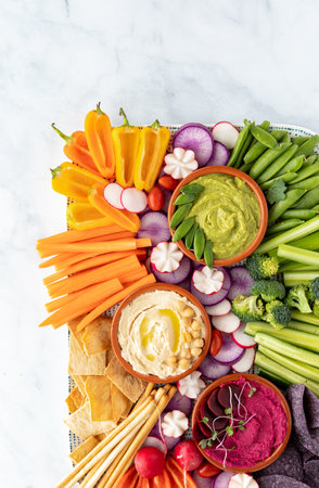 Top down view of a platter filled with cut vegetables, breadsticks and hummus for dipping.の写真素材