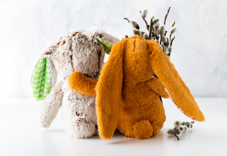 Close up of stuffed bunnies hugging and holding a bouquet of pussy willows. A spring and Easter concept.の写真素材
