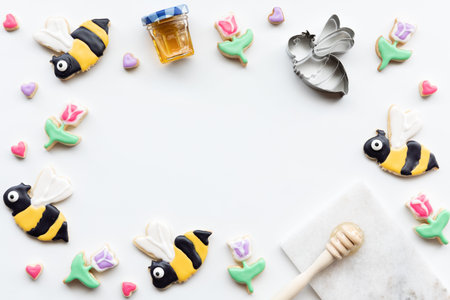 Top down view of a border of sugar cookies in shapes of bees, tulips and hearts. A spring and summer...