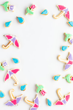 Umbrella, raindrops and tulip sugar cookies in a border frame with copy space in the middle.