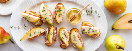 Pear and prosciutto little crostini appetizers, served with honey and thyme.の写真素材