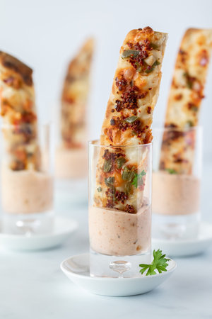 Straight on view of pizza stick shot glass appetizers and dip ready for a party.