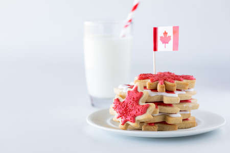 Canada flag sugar cookies on a plate with a glass of milk in behind.の写真素材