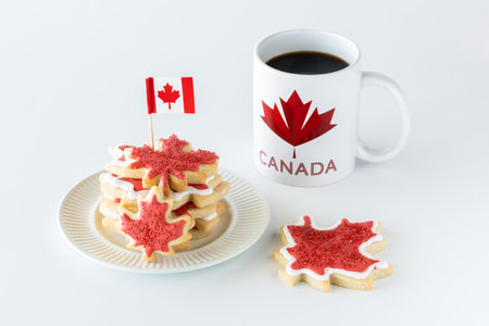 Plate of Canada flag sugar cookies with a cup of coffee against a bright white background.の写真素材