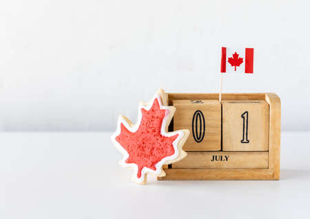 A wooden date block with July first as the date representing Canada Day with a Canada flag sugar cookie in front.の写真素材