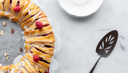 Half of a raspberry crescent ring taken from above with a plate and spatula and copy space in the...