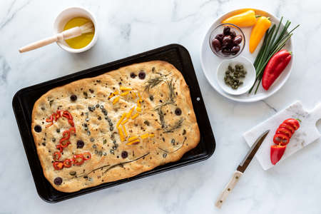 Top down view of a focaccia bread topped with various vegetables forming the numbers 2022. New year concept.の写真素材