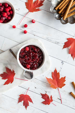 Top down view of a bowl of homemade cranberry sauce surrounded by maple leaves.の写真素材