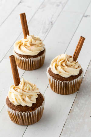 Three homemade pumpkin spice cupcakes topped with cream cheese frosting.の写真素材