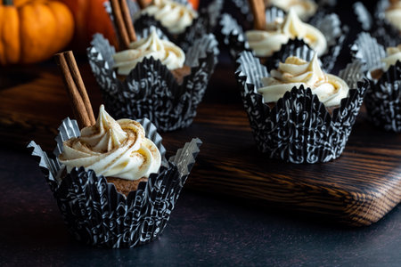 Close up of pumpkin spice cupcakes on a wooden board with one in front.