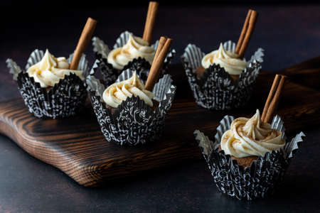 Pumpkin spice cupcakes with cream cheese frosting against a black background.の写真素材