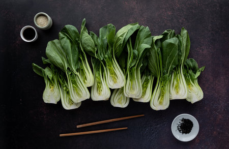 Top down view of bok choy clusters with soy sauce, sesame seeds and chop sticks