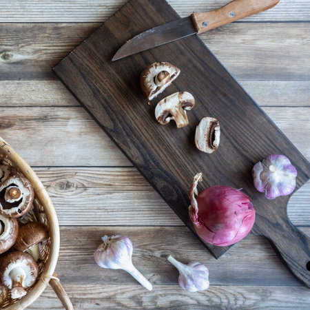 Freshly cut cremini mushrooms on a wooden cutting board.