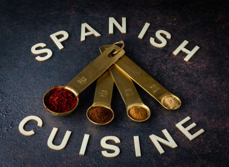 Measuring spoons filled with various spices used in Spanish cooking.の写真素材