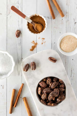 Top down view of a bowl of candied pecans surrounded by ingredients to make themの写真素材