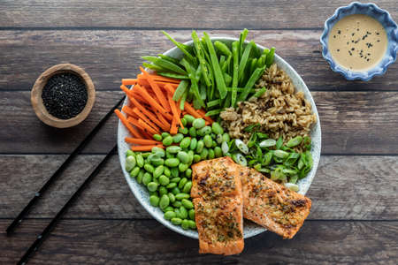 Top down view of a fresh Asian salmon salad bowl with dressing and black sesame seeds.の写真素材