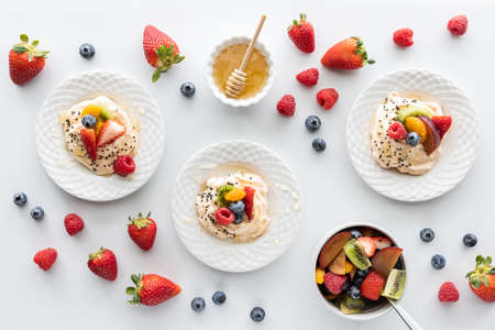 Homemade meringues topped with fresh fruit salad and honey.の写真素材