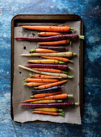 Roasted rainbow carrots on a parchment lined baking sheet.の写真素材