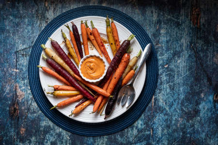 A round dish filled with roasted rainbow carrots and sriracha mayo dip.の写真素材
