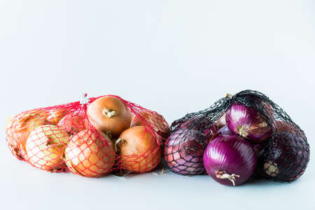Mesh bags of onions isolated against a white background.の写真素材