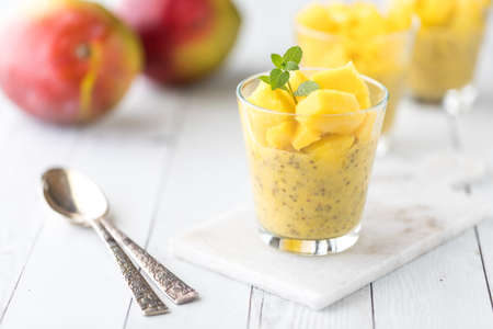 Refreshing mango chia pudding with others in soft focus in behind.の写真素材
