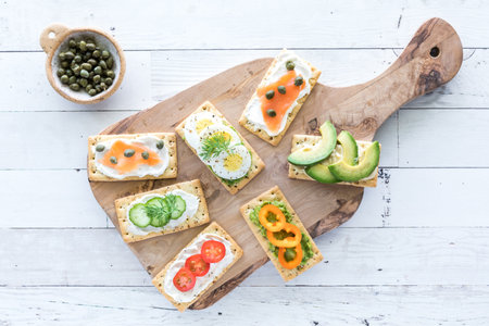 A wooden board with everything crackers and various fresh toppings.