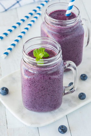 Two jar mugs filled with a healthy blueberry smoothie.