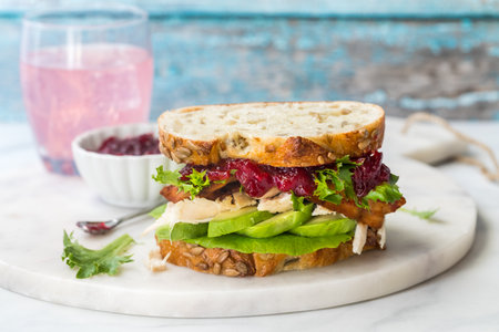 A turkey sandwich with avocado and cranberry sauce on multigrain bread.の写真素材