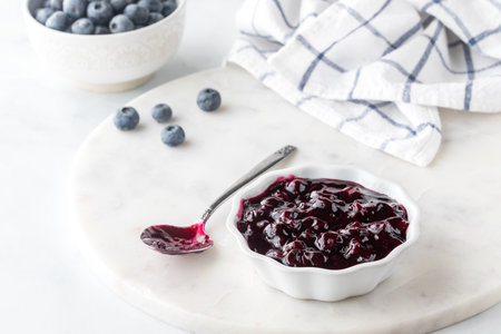 Close up view of a bowl of sweet homemade blueberry sauce on a marble slab.の写真素材