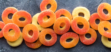 A narrow view of bright colourful sugar coated peach flavoured gummy rings.の写真素材