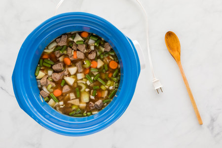A crock pot filled with homemade prepared beef stew ready for cooking.