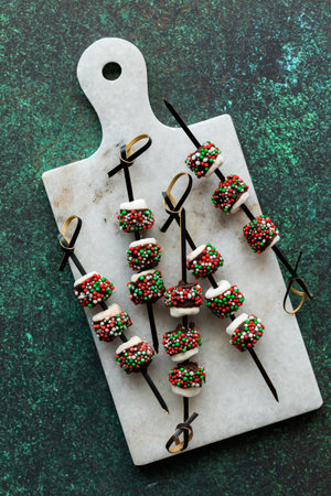 A small marble slab topped with chocolate dipped picks covered in sprinkles.