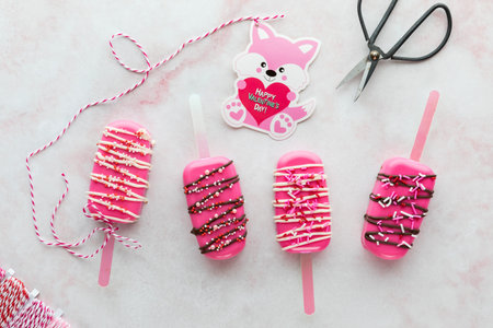 Homemade Valentine cakesicle treats with a Valentine card attached to one.の写真素材