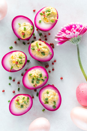 Bright pink devilled eggs garnished with chives and pink peppercorns, for Easterの写真素材